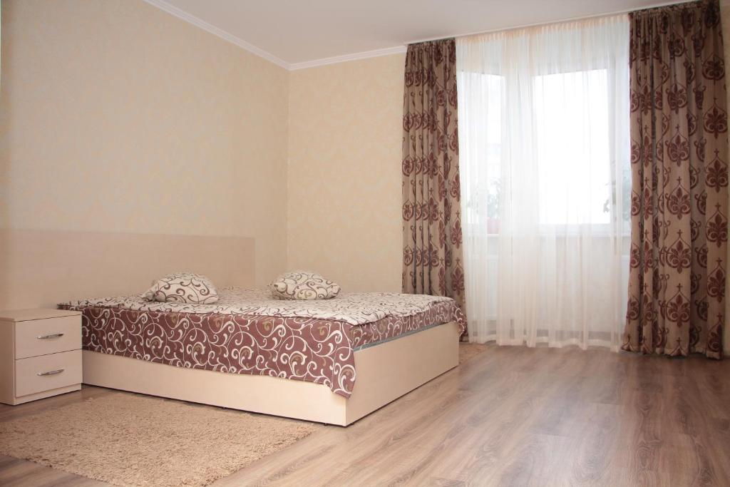 a bedroom with a bed and a window with curtains at Osokorky Apartments in Kyiv