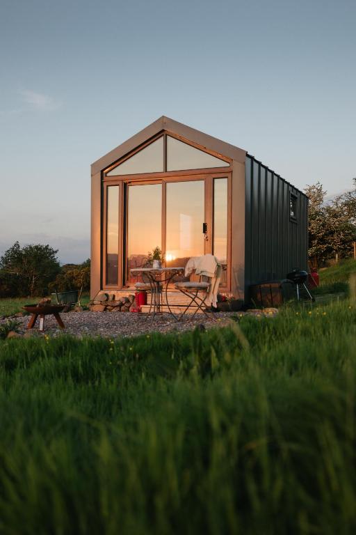 a small cabin with a table in a field at Oaklane Glamping Cabins in Kenmare