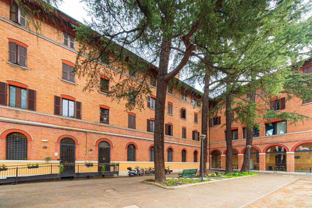 a large brick building with trees in front of it at Il Villaggio di ABITABO in Bologna