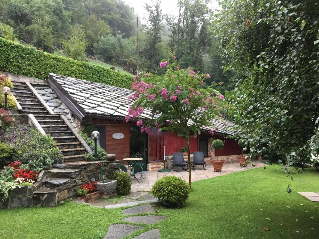 un jardin avec un petit bâtiment rouge orné de fleurs roses dans l'établissement BALMA DEI CUP con SPA privata su richiesta, à Pont Canavese