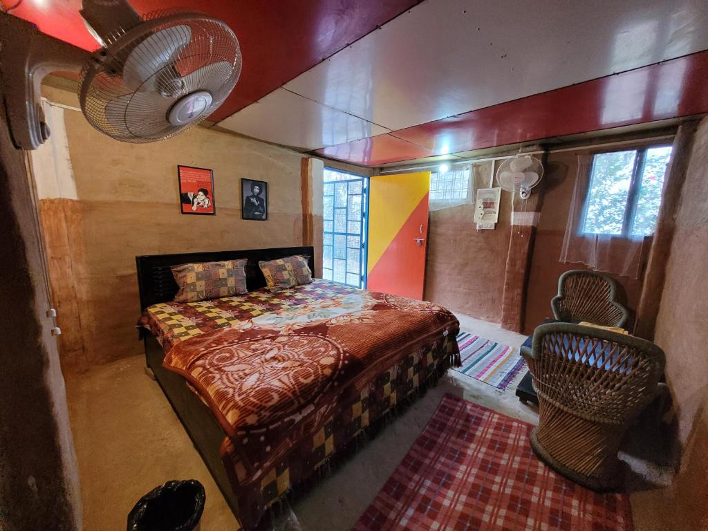 11 Gaon Mudhouse Homestay في لانسداون: غرفة نوم بسرير ومروحة