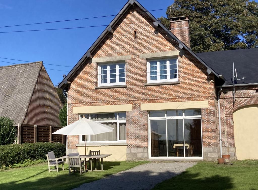 una casa de ladrillo con mesa y sombrilla en La Canuche Appartement avec jardin, en Pleine-Sève