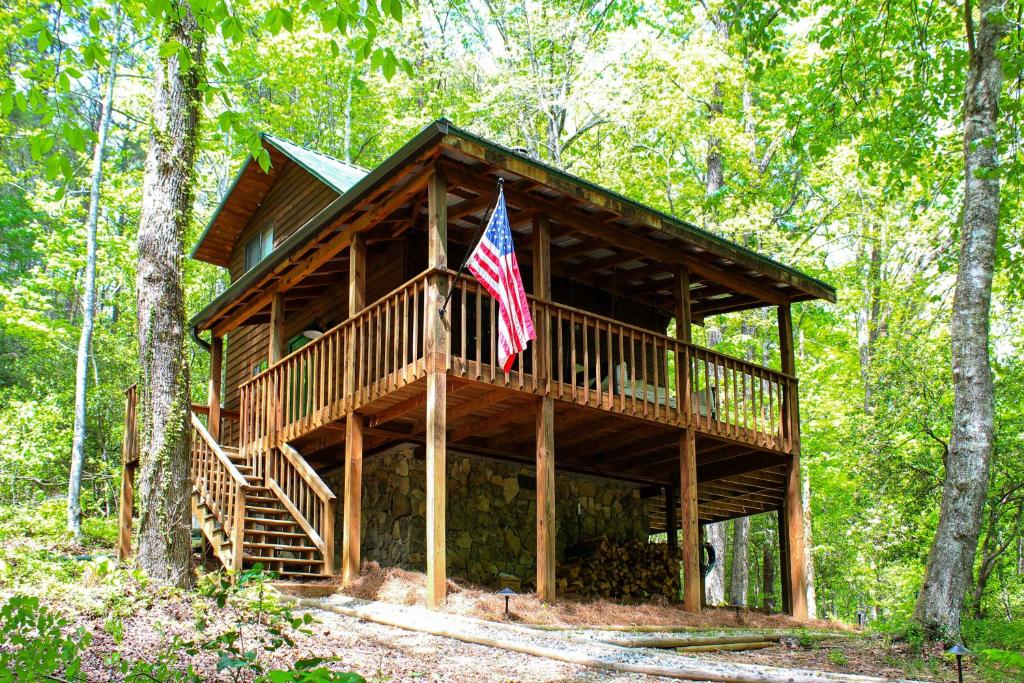 Una casa en el árbol con una bandera estadounidense. en Sautee Nacoochee Mtn Paradise with Spacious Deck!, en Sautee Nacoochee