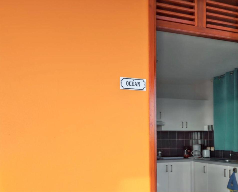 ブイヤントにあるAppartement d'une chambre avec vue sur la mer terrasse amenagee et wifi a Bouillante a 4 km de la plageの台所の看板が入ったオレンジの壁