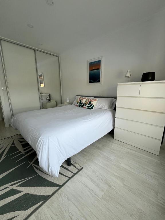 een slaapkamer met een groot wit bed en een dressoir bij Apartamento en Somo cerca de la playa totalmente equipado - Somocubas in Somo