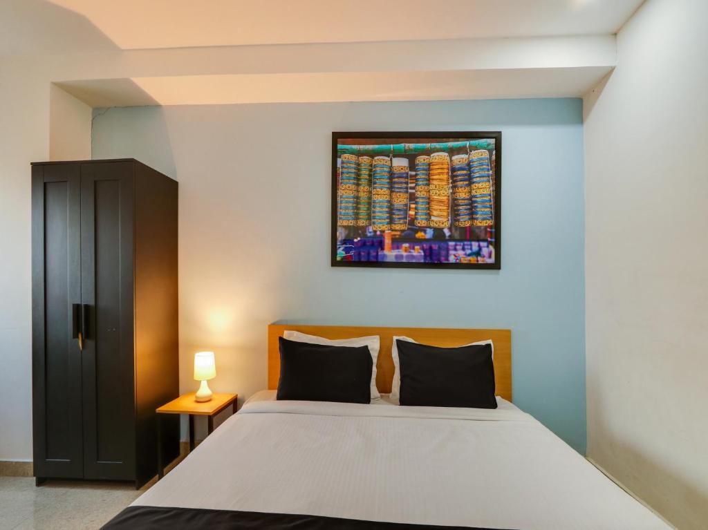 1 dormitorio con 1 cama y una pintura en la pared en Super Collection O QUALIA PRIME HOTEL NEAR NEXUS MALL, en Hyderabad