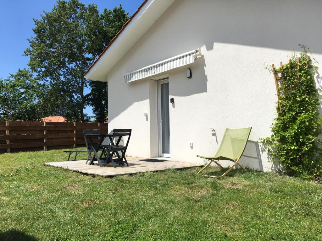 a group of chairs sitting on a porch next to a house at Chambre indépendante et paisible dans maison neuve in Mimizan