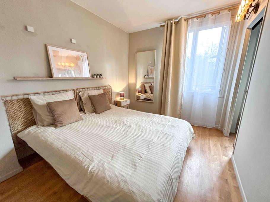 a bedroom with a large white bed with a window at Charmant T2 aux portes de Paris in Aubervilliers