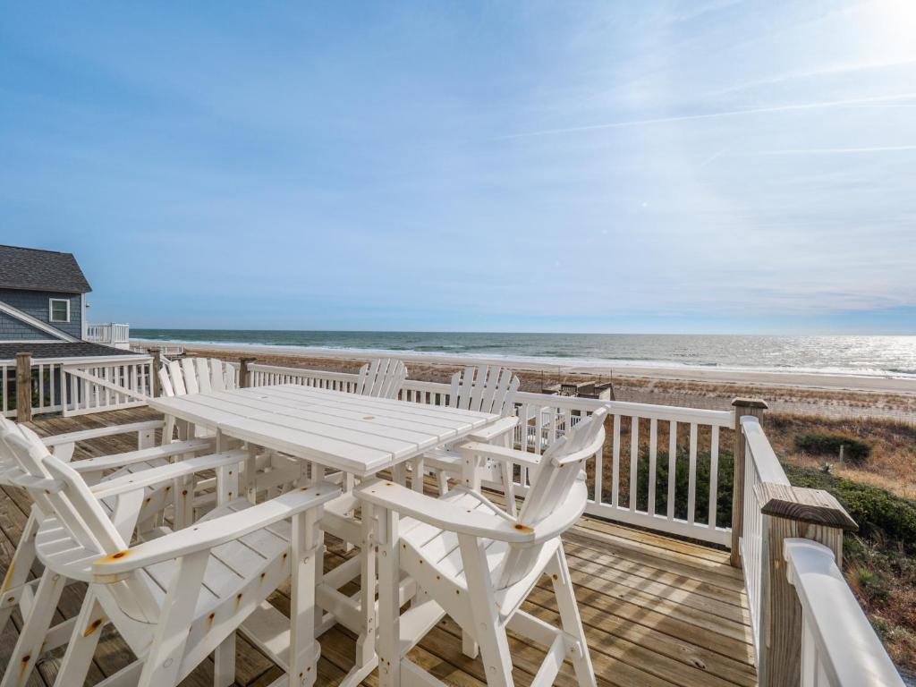 a white table and chairs on a deck with the ocean at C-Maid in Surf City