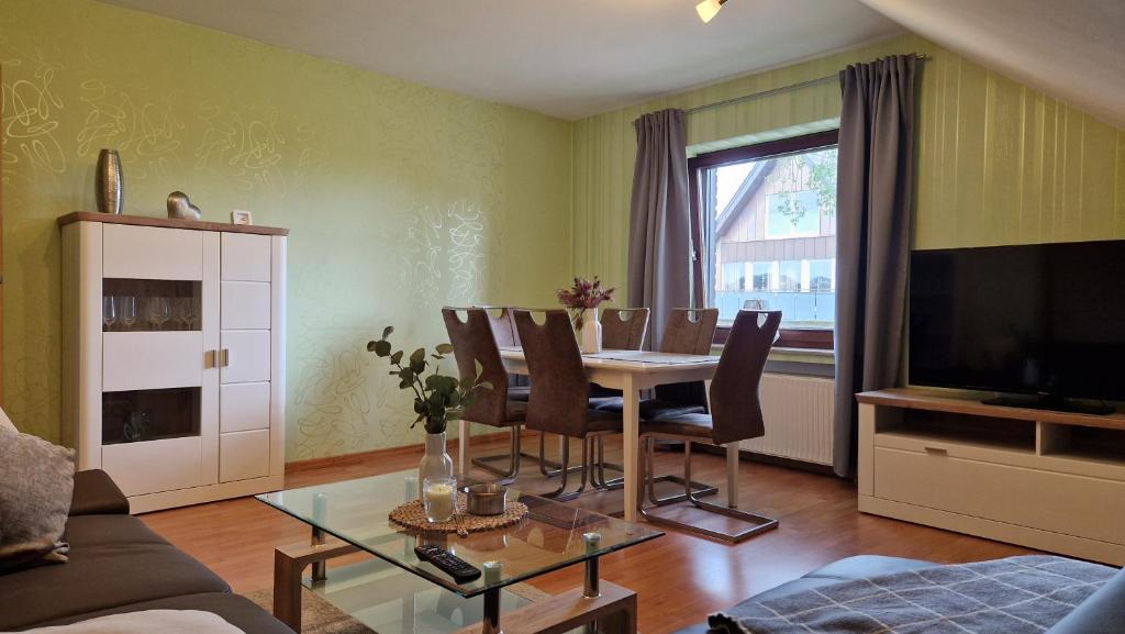 - un salon avec une table, des chaises et une télévision dans l'établissement Ferienwohnung Naturpunkt, à Isselburg