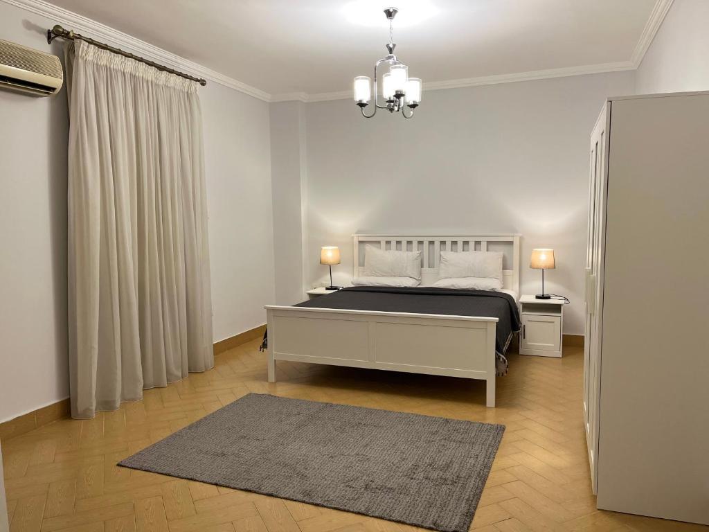 ein weißes Schlafzimmer mit einem Bett und einem Teppich in der Unterkunft Chelay Apartments in Kairo