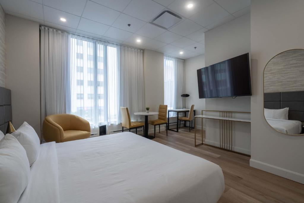 モントリオールにあるホテル トラベロッジ モントリオール センターの白いベッドとテレビが備わるホテルルームです。