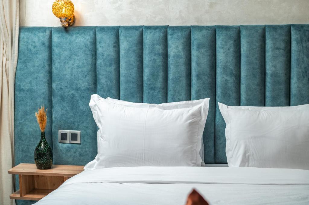 un letto con testiera blu e cuscini bianchi di Maarif Elite Suites a Casablanca