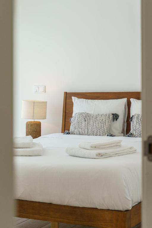 une chambre avec un lit avec des draps blancs et des oreillers dans l'établissement Villa Mauricio, à Mariquiteira