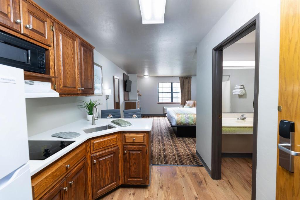 uma cozinha com armários de madeira e uma sala de estar com uma cama em Extended Stay Airport em Green Bay