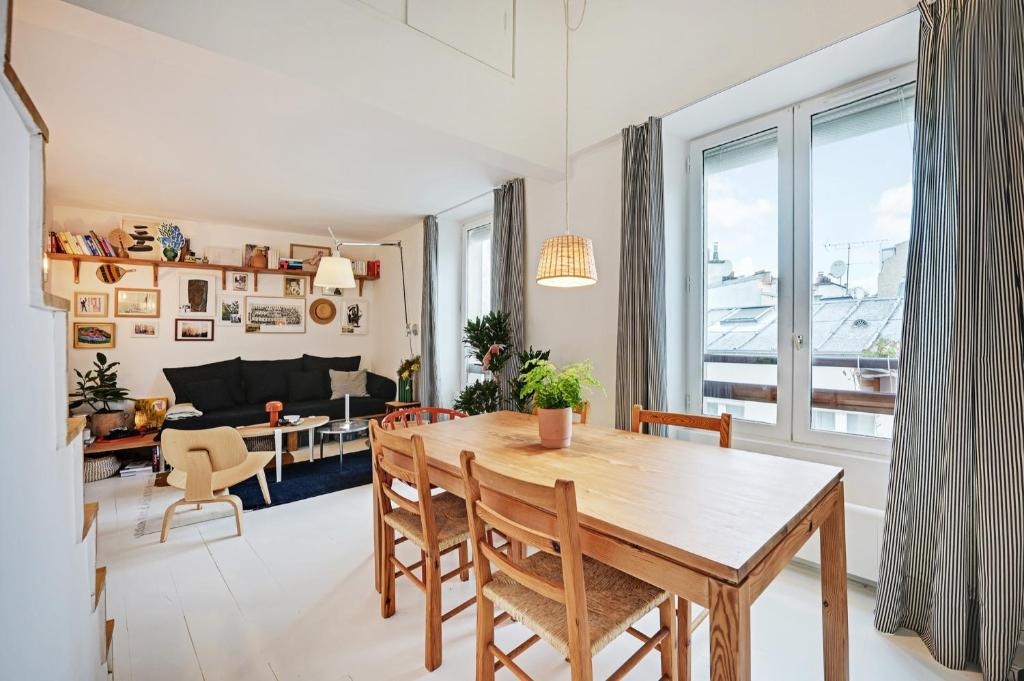 une salle à manger et un salon avec une table et des chaises dans l'établissement Appartement charmant avec vue - Montmartre, à Paris