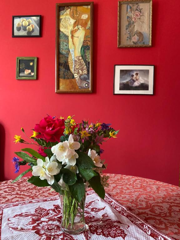 eine Vase mit Blumen auf einem Tisch in einem roten Raum in der Unterkunft Retro big Apartment with two balconies and lift in Karlsbad