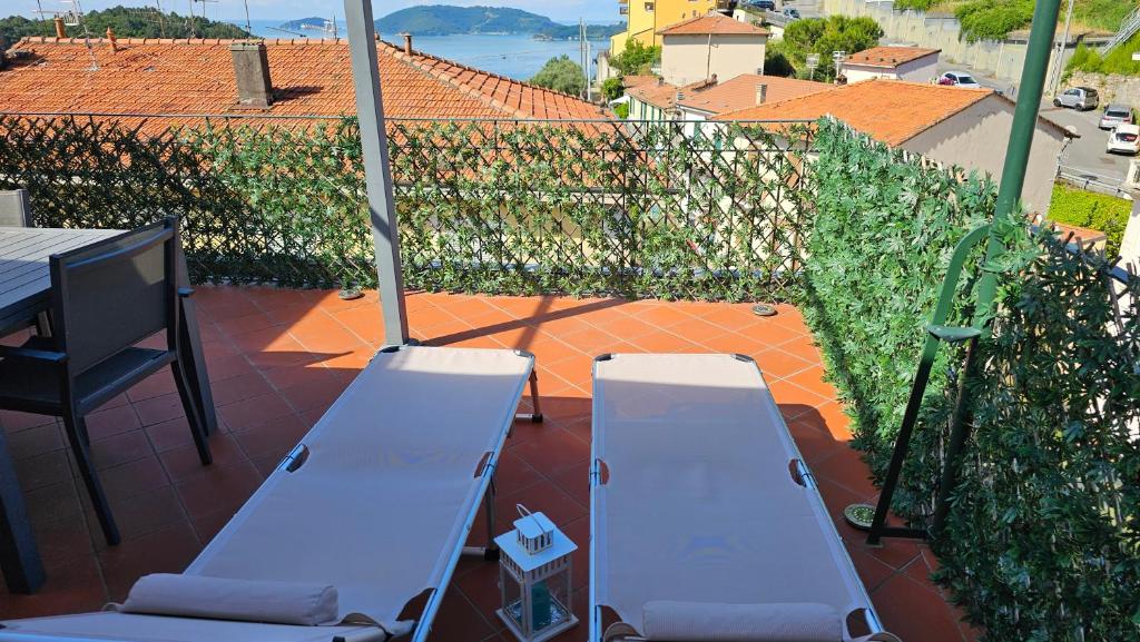 La Terrazza sul Golfo dei Poeti tra Lerici e le Cinque Terre في Pitelli: كرسيين للاستلقاء الأبيض على فناء مع طاولة