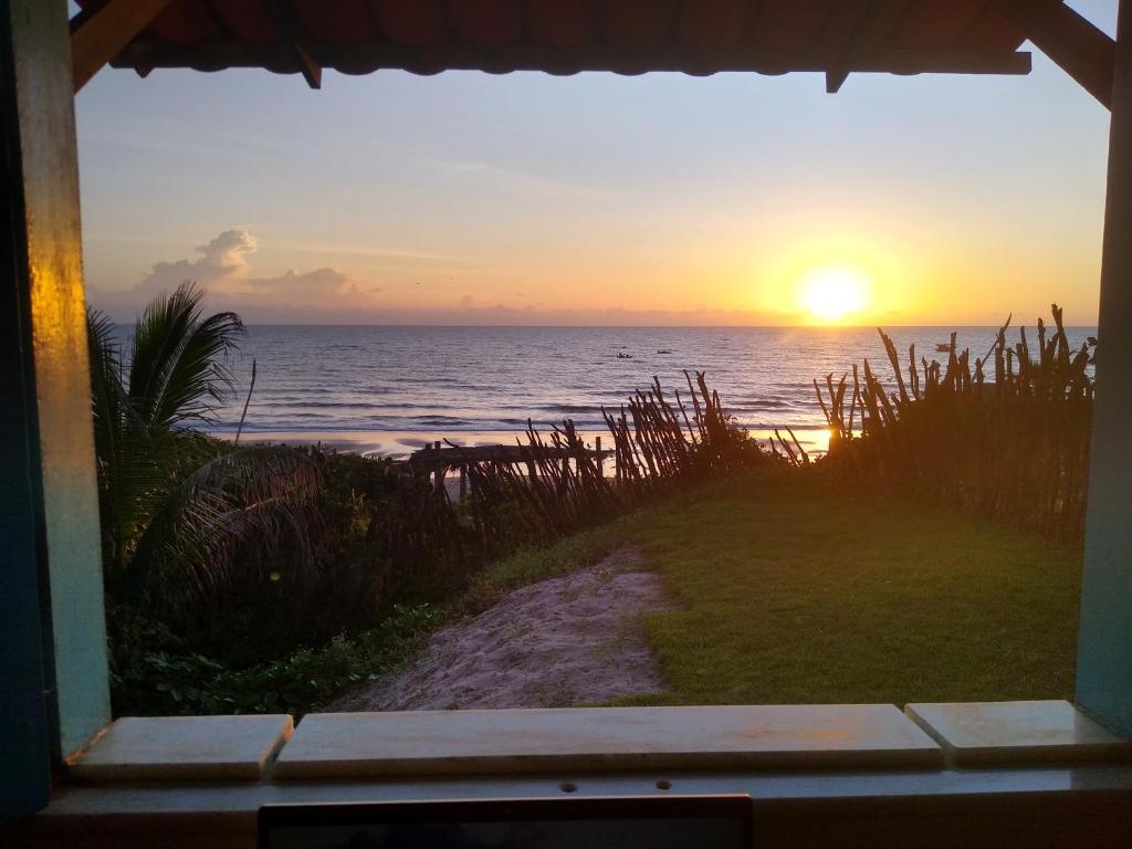 阿拉卡蒂的住宿－Casinha Estrela do Mar o Oceano aos seus Pés，日落时分从窗户欣赏海景