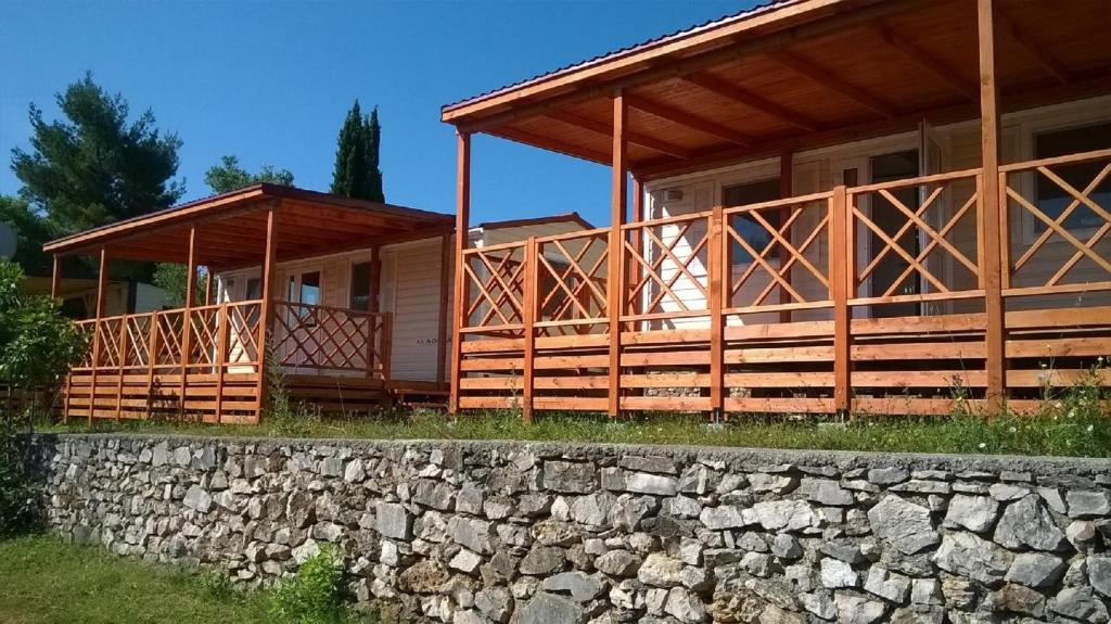 a wooden house with a stone wall next to it at Mobile Homes Murter in Jezera