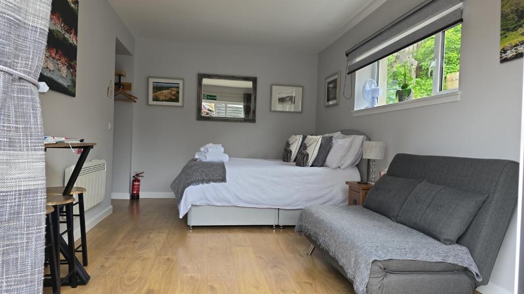 a bedroom with a bed and a couch and a window at 13 Matheson Place in Portree