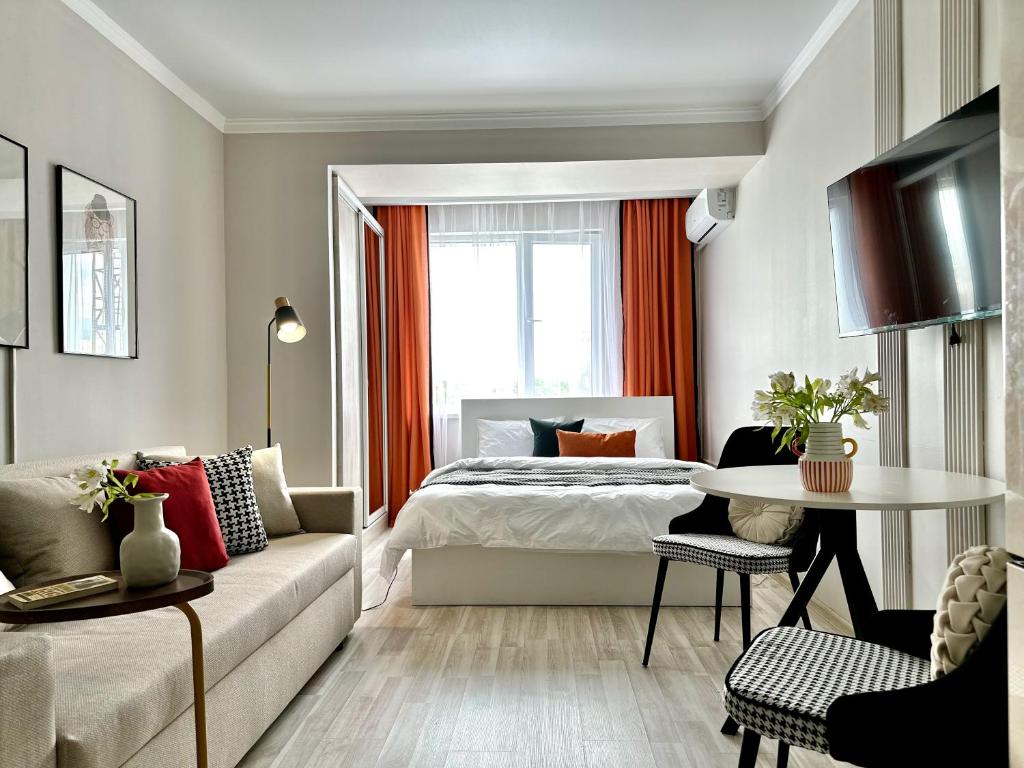 a bedroom with a bed and a table and a couch at Студия ДЭНДИ с видом на горы in Almaty