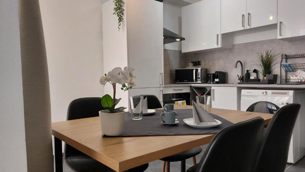 a kitchen with a wooden table with black chairs at Orchidea apartman in Balatonalmádi