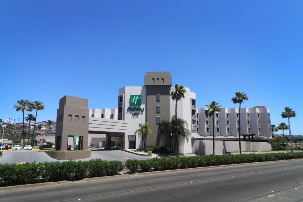 un gran edificio con palmeras frente a una calle en Holiday Inn Tijuana Zona Rio, an IHG Hotel, en Tijuana