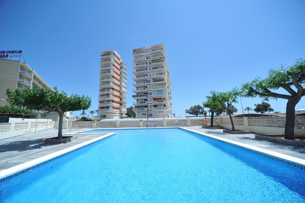 una piscina con árboles y edificios en el fondo en Apartamentos Estoril I - II Orangecosta, en Benicàssim