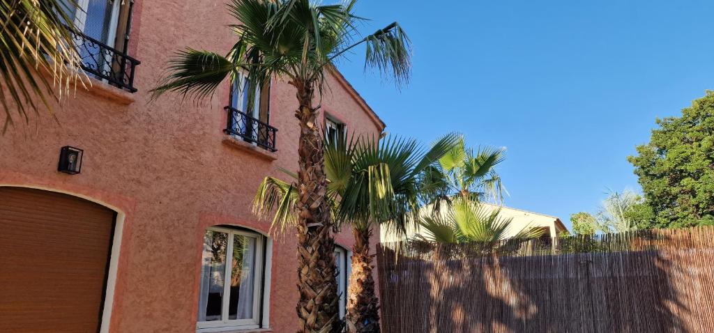un bâtiment avec deux palmiers devant lui dans l'établissement Haut de villa à 700 mètres de la plage, totalement indépendant et accessible par un escalier extérieur, à Sainte-Maxime