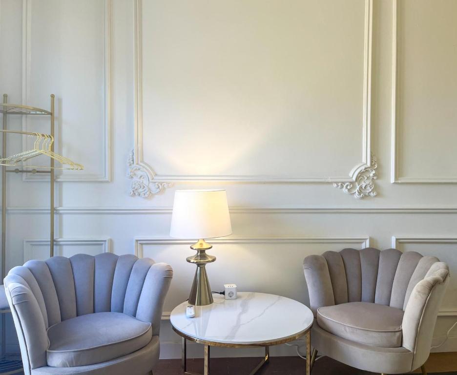 two chairs and a table and a lamp in a room at Apartamentos Loles De Cisneros Catedral in Málaga