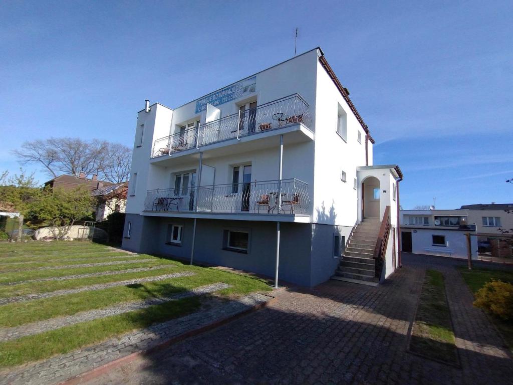 ein weißes Gebäude mit einer Treppe davor in der Unterkunft Dom Gościnny Maja - Pokoje in Mrzeżyno