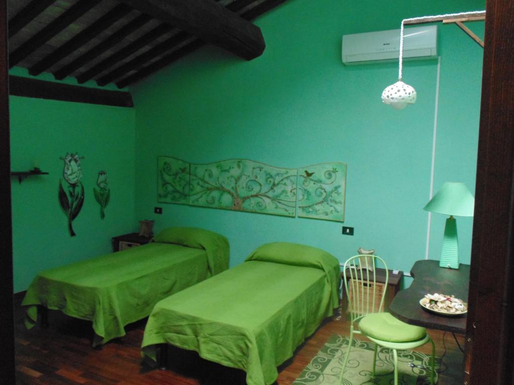 Cette chambre verte comprend 2 lits et une table. dans l'établissement B&B IL Giardino del Borgo, à Veiano