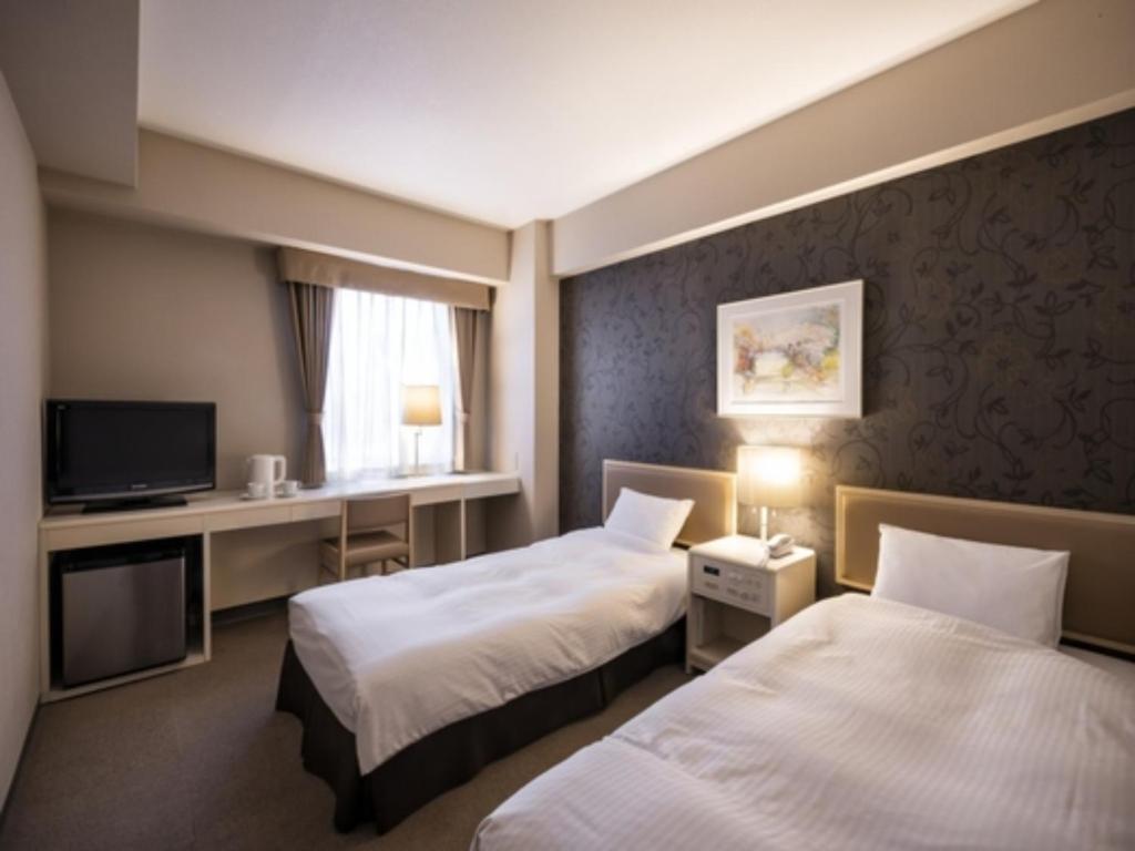 a hotel room with two beds and a desk at Business Inn Norte Nakajima Park - Vacation STAY 08712v in Sapporo