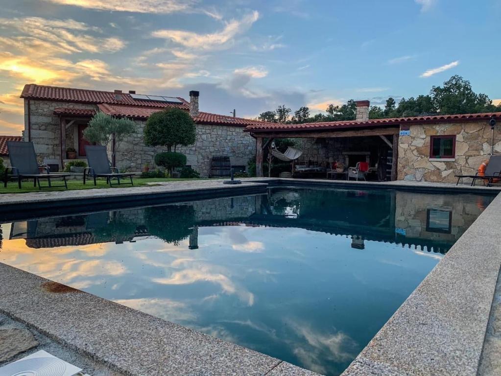 una piscina di fronte a una casa con il cielo di Carya Tallaya - Casas de Campo a Vale das Éguas
