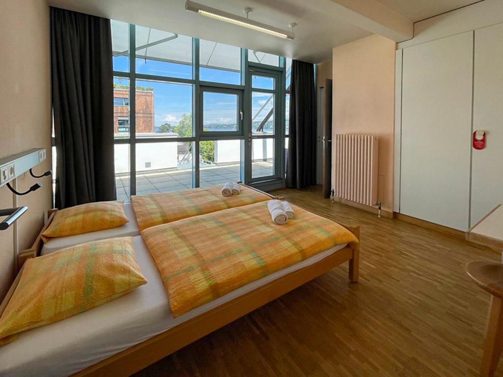 a bedroom with a large bed with a large window at Geneva Hostel in Geneva