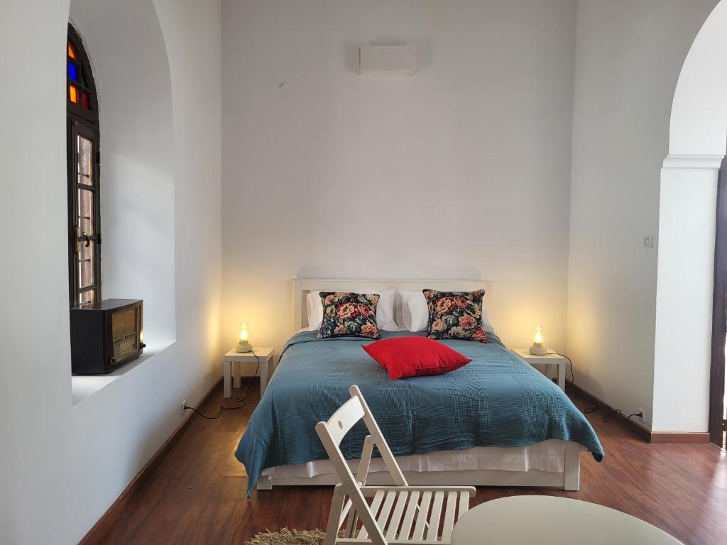 a bedroom with a bed with a blue blanket and red pillows at Riad Tazi Casablanca in Casablanca