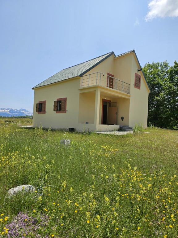 una casa en un campo con un campo de flores en Alpe House Korita en Podgorica