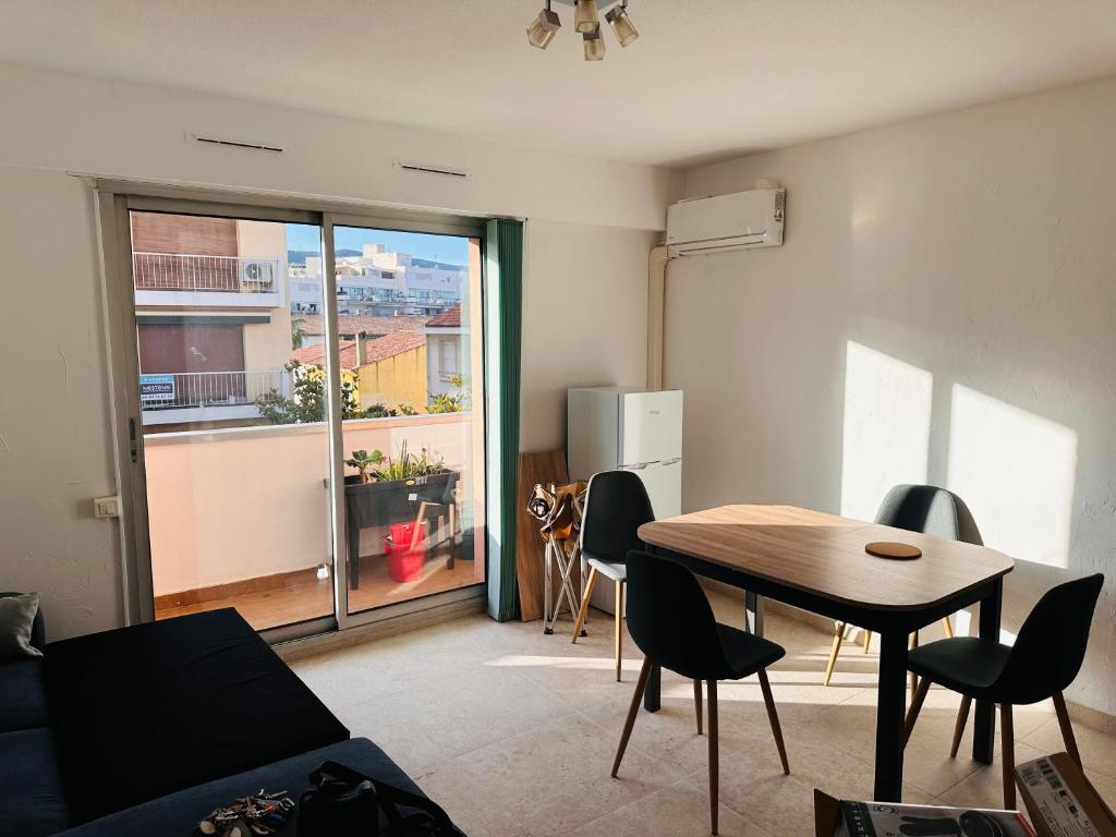un salon avec une table et des chaises et une fenêtre dans l'établissement Appartement Cavalaire proche de la mer , état neuf ,réservation 3 Jours minimum, à Cavalaire-sur-Mer