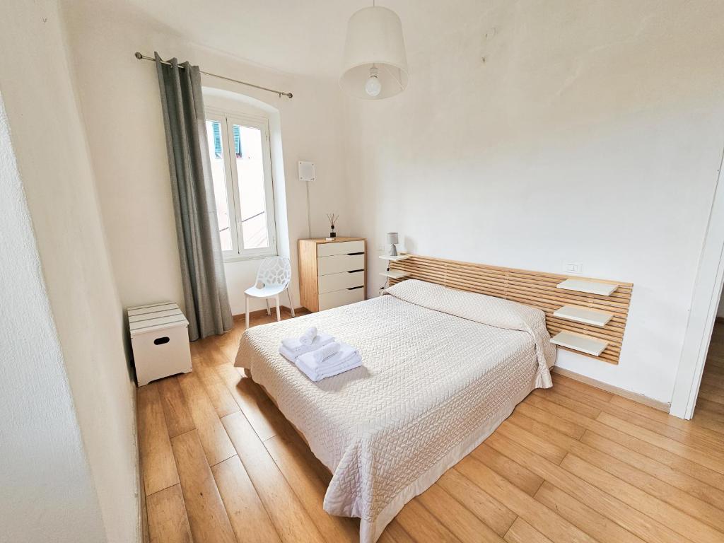 a white bedroom with a bed and a window at Narissara apartment in La Spezia
