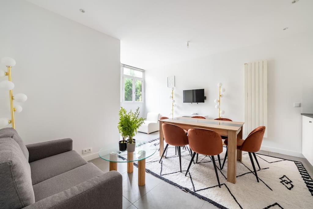 a living room with a couch and a table and chairs at Maison en Centre-Ville - Neuilly in Neuilly-sur-Seine