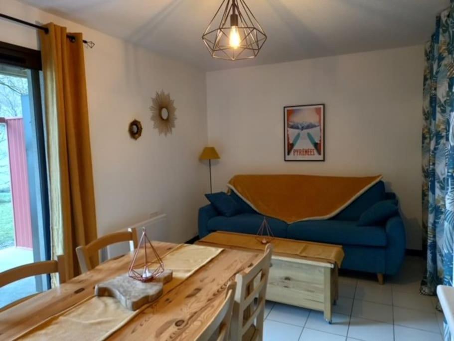 un salon avec un canapé bleu et une table dans l'établissement Appartement Cosy proche St lary et Loudenvielle, à Arreau