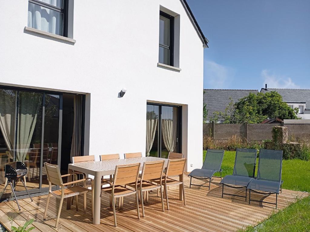 une terrasse en bois avec une table et des chaises dessus dans l'établissement Maison 8 pers, proche plage et commerces, jardin, barbecue, équipements bébé, linge inclus - FR-1-639-122, à Arzon