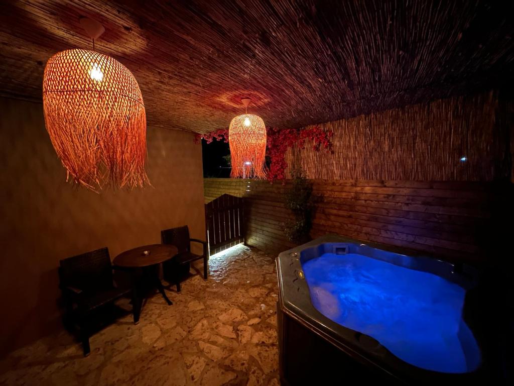 Cette chambre comprend un bain à remous, une table et un lustre. dans l'établissement 4 MOUNTAIN HILLS, à Méga Khoríon
