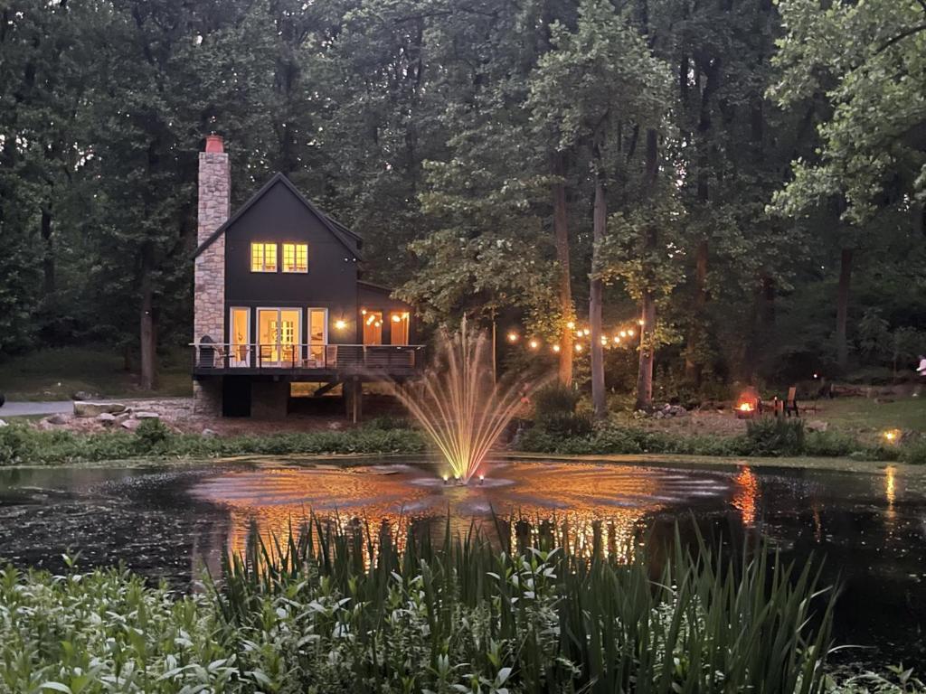 ein Haus inmitten eines Teiches mit einem Springbrunnen in der Unterkunft The Roundtop Chalet romantic couples getaway in Wrightsville