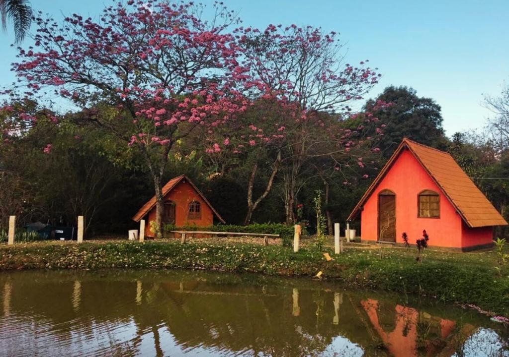 una pequeña casa roja junto a un cuerpo de agua en Pousada Rural Vargem do Cedro, en Belo Vale