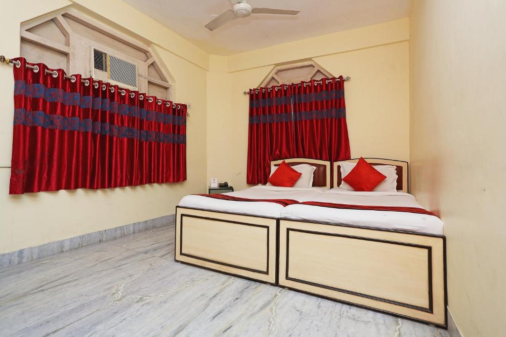 um quarto com uma cama com cortinas vermelhas em Kalighat em Ālīpur