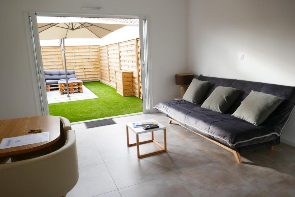 un salon avec un canapé noir et un parapluie dans l'établissement Les Pivoines Maison climatisée, proximité mer, plages et forêts, à Saint-Hilaire-de-Riez