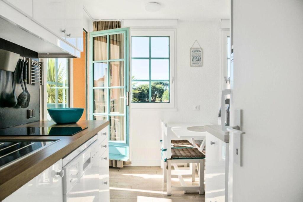 une cuisine avec des armoires blanches et une fenêtre dans l'établissement Résidence Port Bourgenay - maeva Home - Appartement 2 pièces 4 personnes - Sélection MAE-1654, à Talmont-Saint-Hilaire