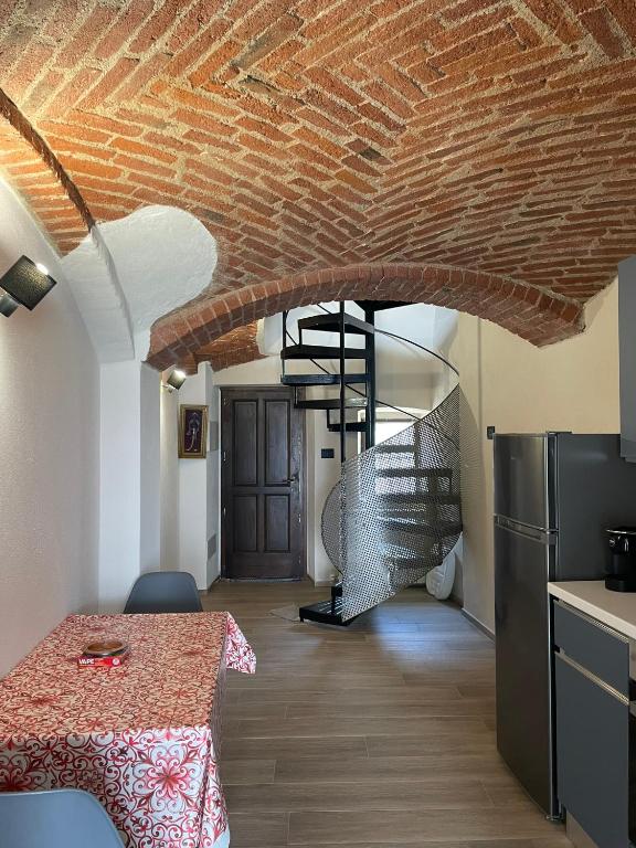 a kitchen with a table and a spiral staircase at Maison Du Bois in Rivarolo Canavese